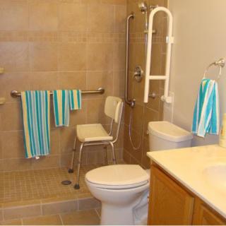 An accessible bathroom equipped with a shower chair, grab bars, and neatly hung striped towels.