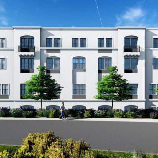A modern apartment building with three stories, featuring multiple windows and surrounded by trees.