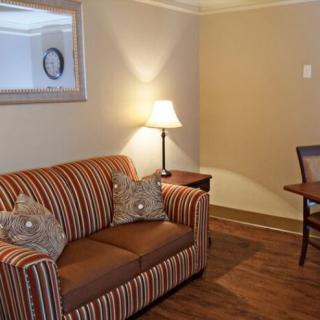 A cozy living room with a striped sofa, an elegant lamp, and a wooden table and chair.