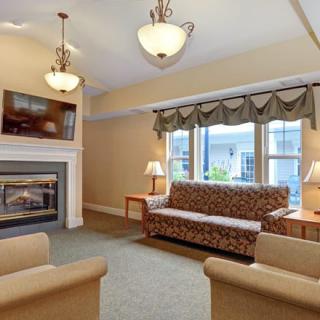 A cozy living room featuring a fireplace, comfortable seating, and large windows.