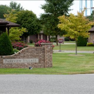 Entrance to a residential community with well-maintained lawns and brick signage.