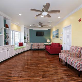 A cozy and modern living room featuring a mix of colorful furnishings, hardwood flooring, and ample natural light.