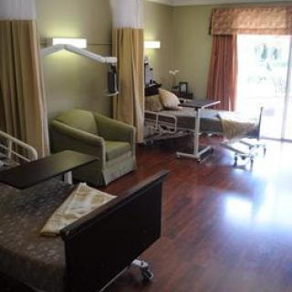 A hospital room with patient beds, chairs, and medical equipment.