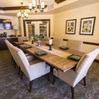 A spacious dining room with a long wooden table, elegant chairs, and chic decor.