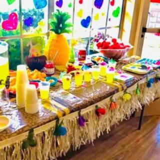 A vibrant tropical-themed party table with drinks and colorful decorations.