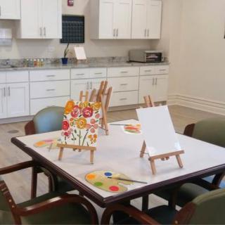 A creative workspace with easels and painting supplies set up on a table in a kitchen area.