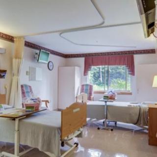 A well-lit hospital room with two beds and seating area.