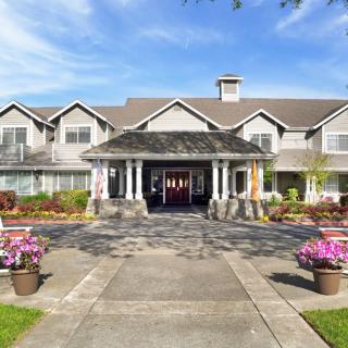 A beautifully landscaped building entrance with flowers and a clear blue sky.