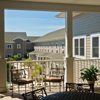 A cozy patio overlooking a building with outdoor seating and lush greenery.