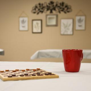 A cozy setting featuring a checkers board game and a red cup, perfect for a casual game night.