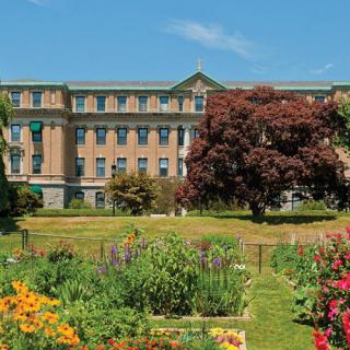 A beautiful garden with colorful flowers and trees in front of a historic building.