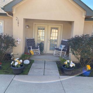 Front porch of a house with rocking chairs and plants.