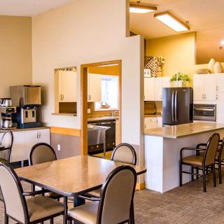 A cozy dining area with a kitchen featuring tables, chairs, and a coffee machine.