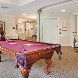 A stylish game room featuring a classic billiards table with purple felt, set in an elegantly designed interior.