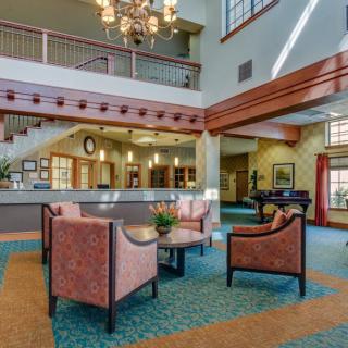 A spacious lobby area with comfortable seating, a chandelier, and a reception desk.