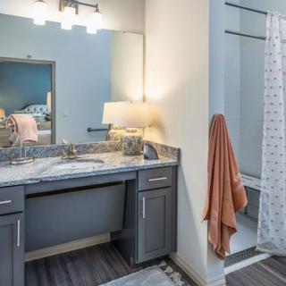 A modern bathroom featuring a vanity with dual sinks, a large mirror, and a shower area with a patterned curtain.