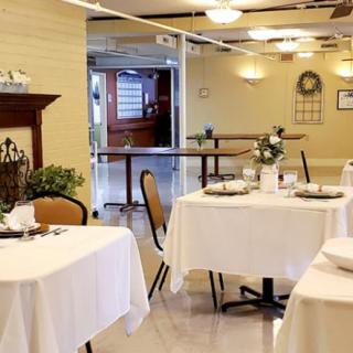 An elegantly set dining area with tables covered in white tablecloths.