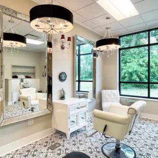 A modern and stylish salon interior with elegant chandeliers, large mirrors, and natural light.