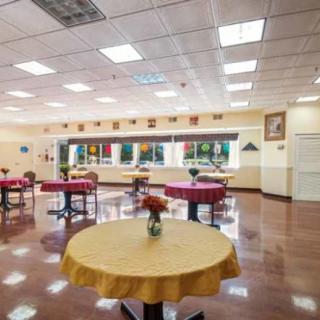 An empty cafeteria with round tables set up, each adorned with a vase of flowers.