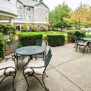 A serene outdoor patio with tables and chairs surrounded by lush greenery.