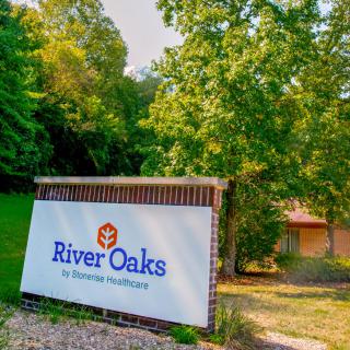 Entrance to River Oaks surrounded by lush greenery.