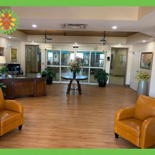 A well-decorated lobby with comfortable seating and a central table, surrounded by decorative plants and artwork.
