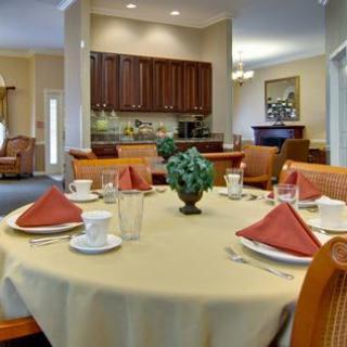 An elegant dining room with a neatly set table, featuring red napkins and white dinnerware.