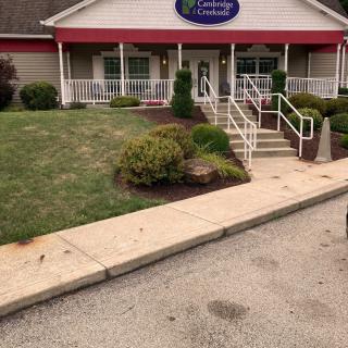 A restaurant entrance with a red awning and landscaped surroundings.