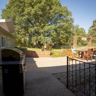 A sunny backyard patio with outdoor furniture and a garden area.
