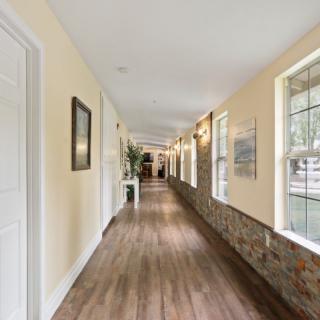 A long, well-lit hallway with wooden floors and large windows.