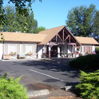 A welcoming building surrounded by greenery and a parking area.