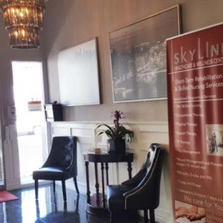 A welcoming waiting area with chairs, a small table with a plant, and a chandelier.
