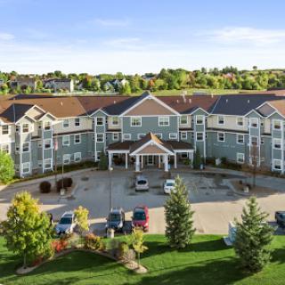 A picturesque hotel surrounded by lush greenery and a spacious parking area.