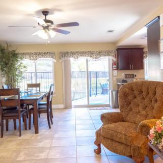 A cozy living and dining space with a ceiling fan and sliding glass doors.