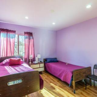 A cozy bedroom with two beds and purple walls.