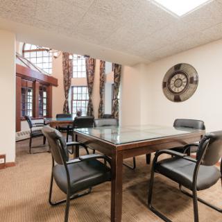 A modern meeting room featuring a glass conference table and ergonomic chairs, bathed in natural light.