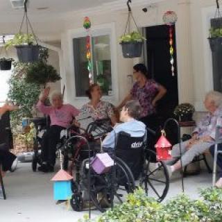 A group of elderly individuals enjoying a conversation outdoors in a nursing home setting.