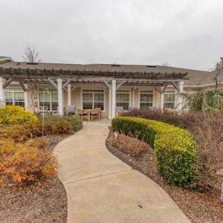 A walkway leading to a building with landscaped gardens.