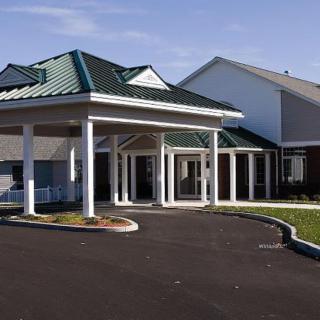 A building with a covered entrance and columns, featuring a green roof.
