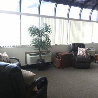 A cozy waiting room with armchairs and large windows letting in natural light.
