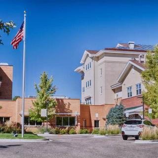 A hotel building with a flagpole and parking area under a clear blue sky.