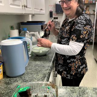A person is smiling while preparing food in a kitchen.