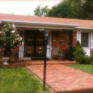 A charming brick house with a small front garden and pathway leading to the entrance.