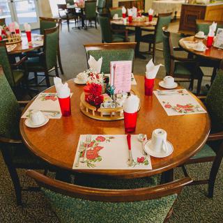 A warmly set dining table with placemats, red cups, and arranged napkins in a restaurant setting.