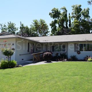 A well-maintained single-story house with a lush green lawn and exterior garden.