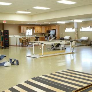A spacious rehabilitation center equipped with therapy tables and exercise equipment.