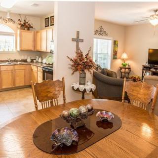 An inviting open-plan home interior featuring a wooden dining table, a kitchen with light wood cabinets, and a cozy living area.