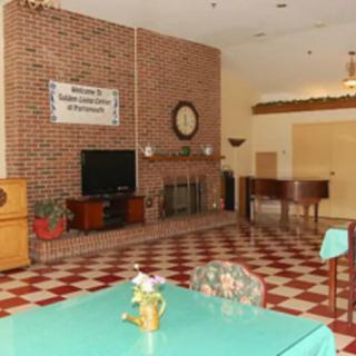 A cozy living room featuring a brick wall with a fireplace, television, and piano, adorned with checkered flooring.
