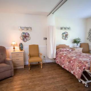A cozy hospital room with a bed, chairs, and decorative items on the wall.