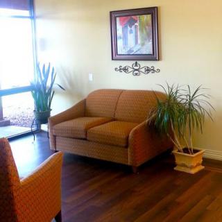 A cozy waiting area with a sofa, plants, and artwork on the wall.